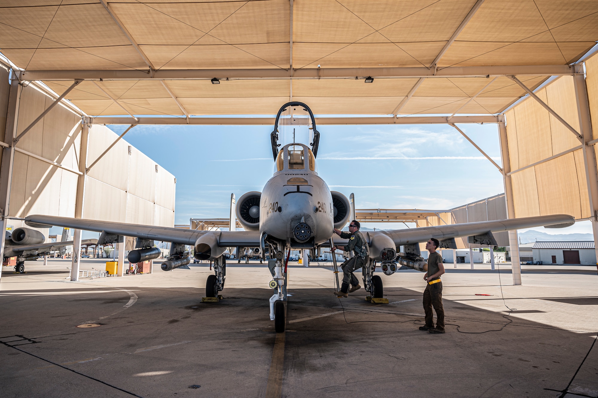 A photo of an aircraft sitting under a sun shade on the flight line.