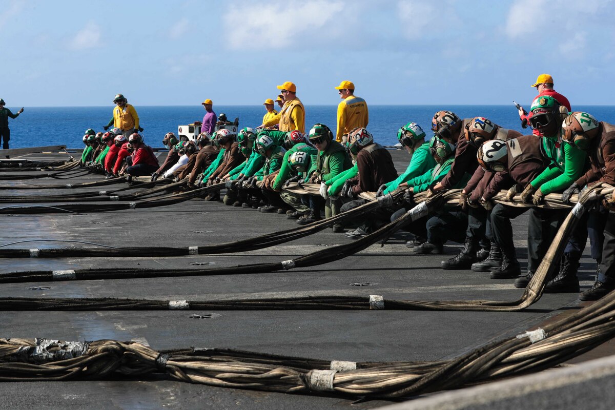 Sailors set up a barricade on the deck of a ship.