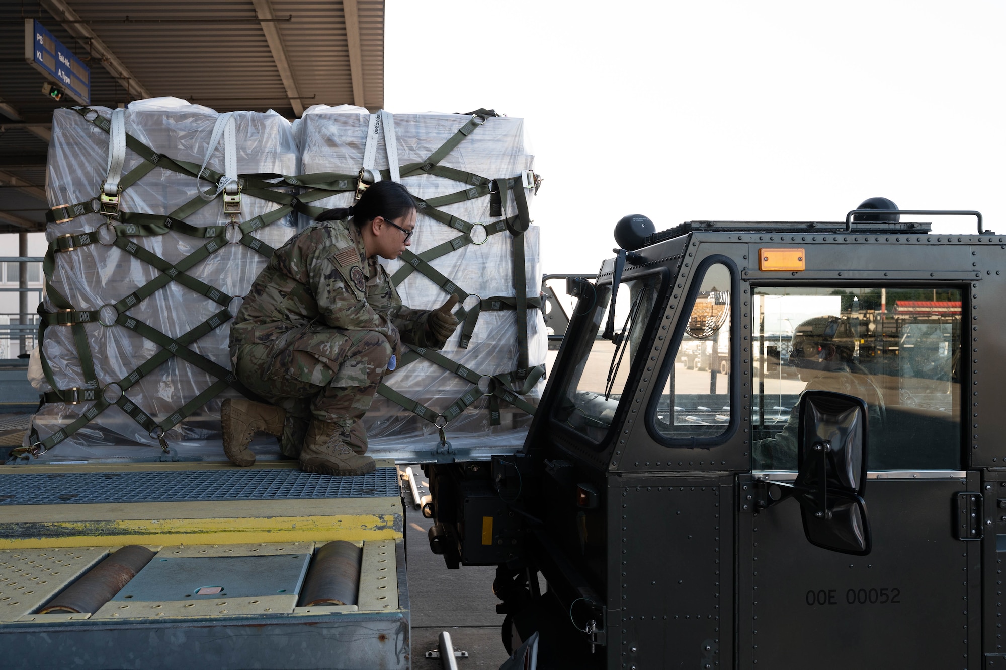 An Airman directs a pallet of infant formula onto a 60K cargo loader driven by another Airman.