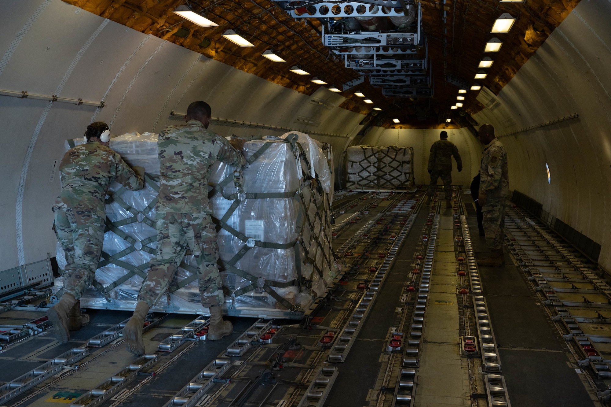 Port dawgs push a pallet of infant formula inside a commercial aircraft.