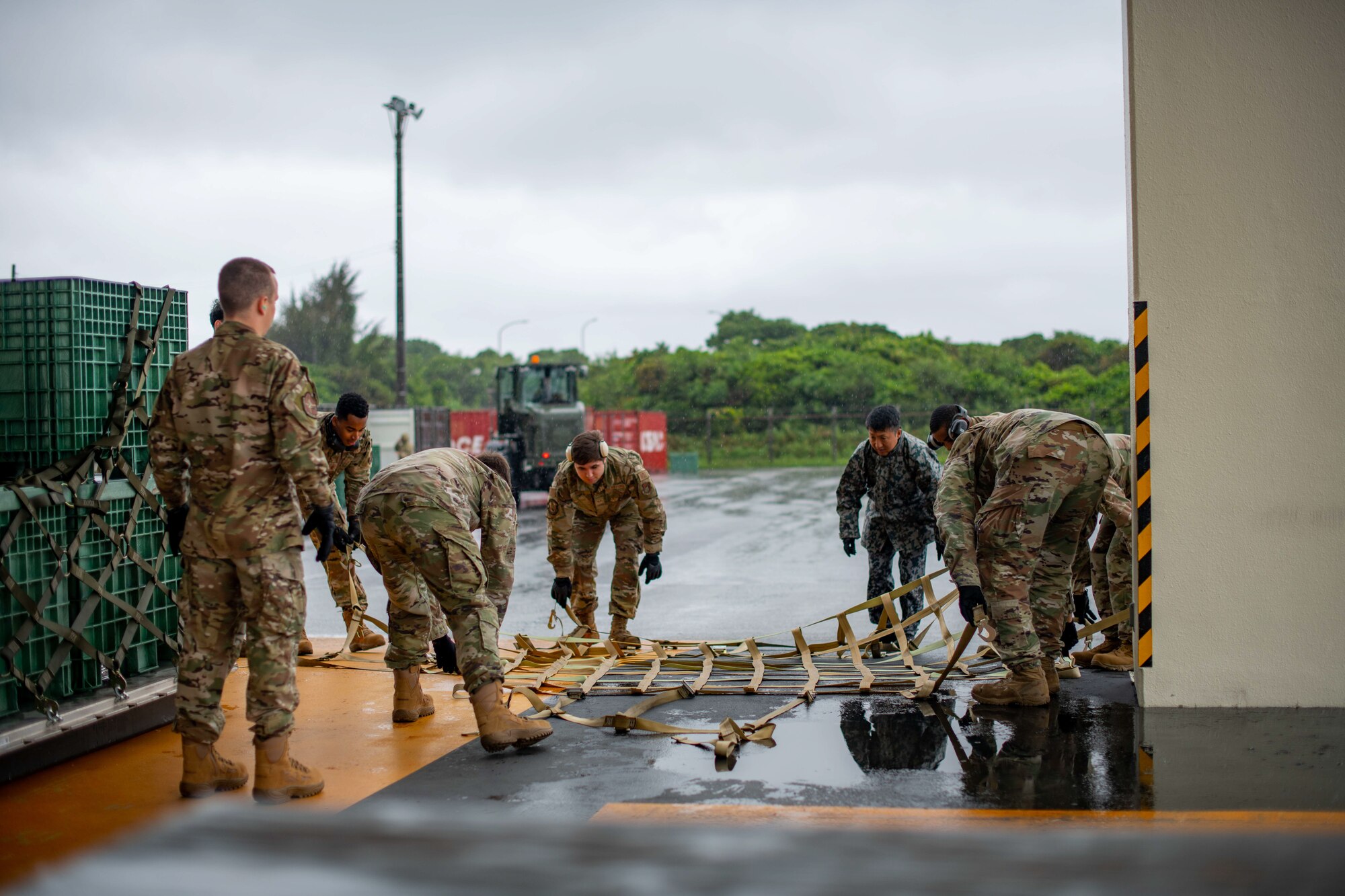 Airmen and a JASDF service member practice preparing cargo.