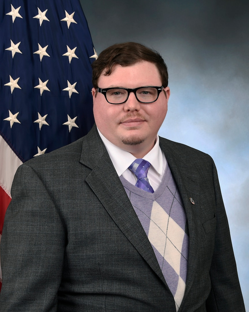 Official photo man in suit in front of American and DLA flags