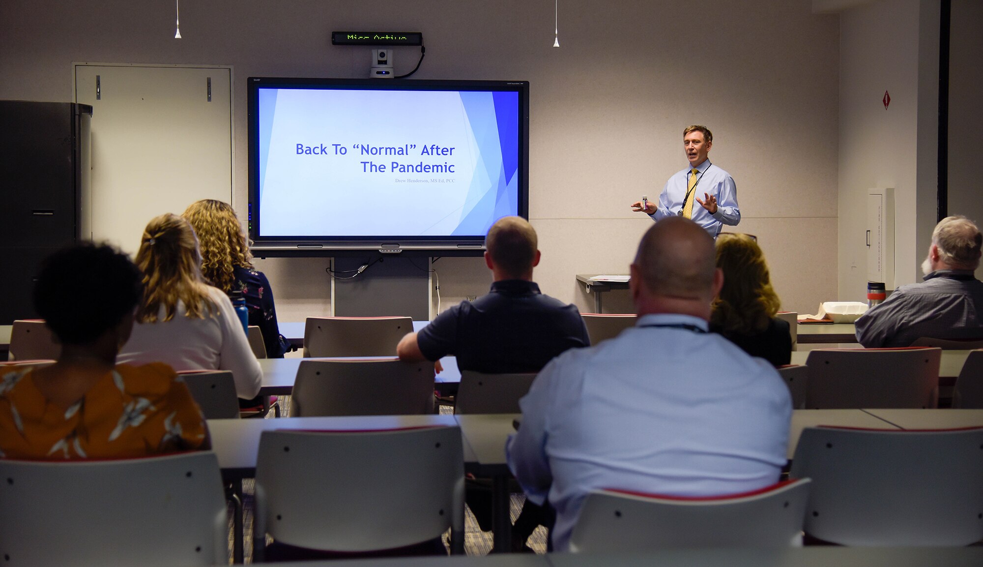 DLA Land and Maritime Deputy Commander Kenneth Watson in front of a Powerpoint in a classroom setting.