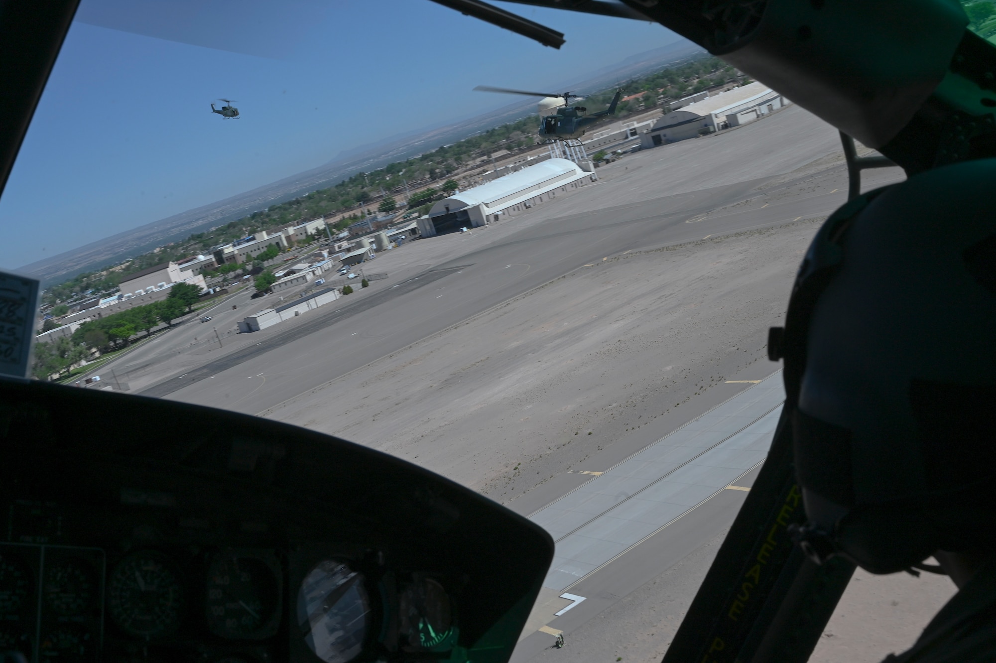 The UH-1 Iroquois take off in a staggered formation for an orientation flight as part of the annual Spouses Day event at Kirtland Air Force Base, New Mexico. May 14, 2022. This year spouses from the Air National Guard were able to attend spouse day as it was opened up this year for different sections in units. (U.S. Air Force photo by Amn Tallon Bratton.)