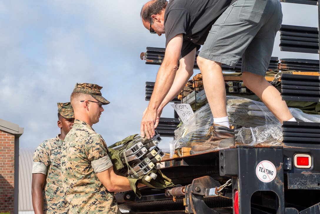 Allen Smithwick, a vehicle operator for motor transport, right, passes a cot to U.S. Marine Corps Cpl. Logan Youngblood, a range coach assigned to Headquarters and Headquarters Squadron, Marine Corps Air Station (MCAS) Cherry Point, during HURREX  at the Cherry Treehouse, MCAS Cherry Point, North Carolina, May 16, 2022. HURREX is a week-long hurricane preparedness exercise held across the installation that’s intended to increase MCAS Cherry Point’s readiness for the Atlantic hurricane season. (U.S. Marine Corps photo by Lance Cpl. Lauralle Walker)