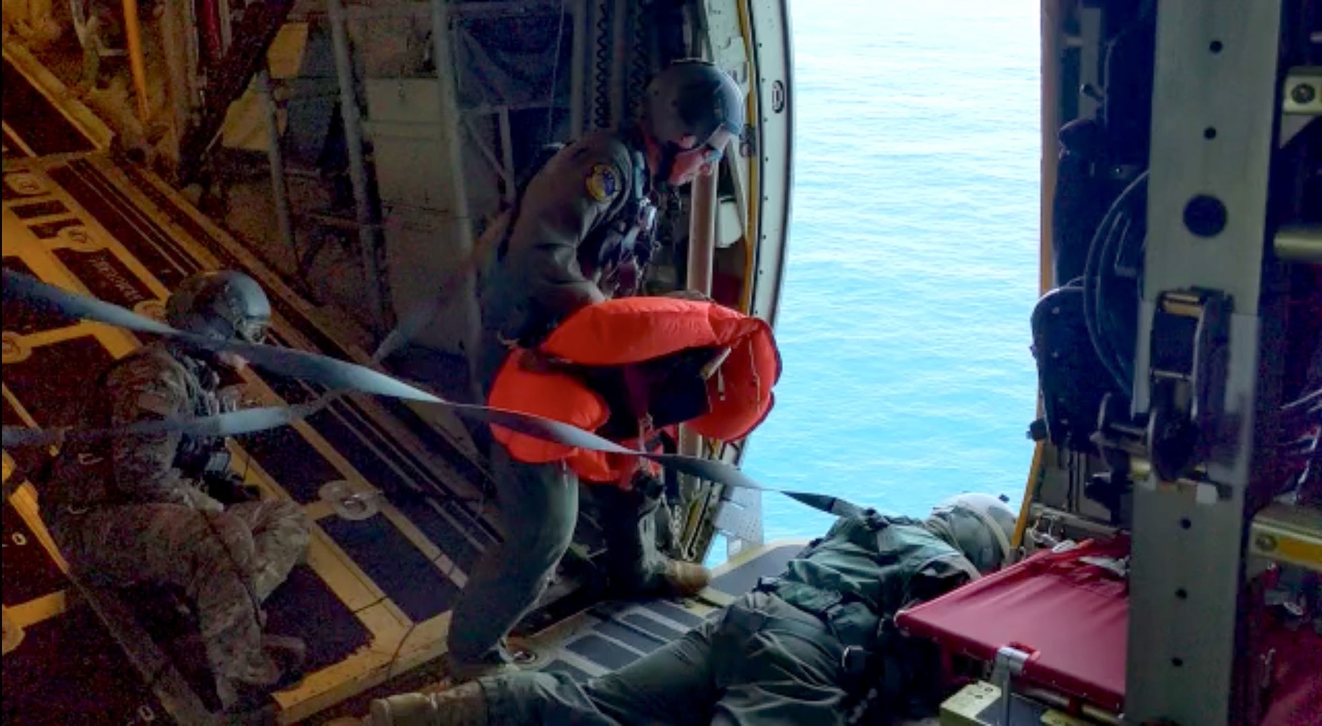 Loadmasters assigned to the 106th Airlift Wing of the New York Air National Guard prepare to toss medical supplies out of an HC-130J Combat King II search and rescue aircraft to the crew of a sailboat 1,200 miles east of Long Island in the Atlantic Ocean May 20, 2022, in this video capture image. The wing dropped medical supplies to the crew of the Namah to treat a crewmember with serious burns.