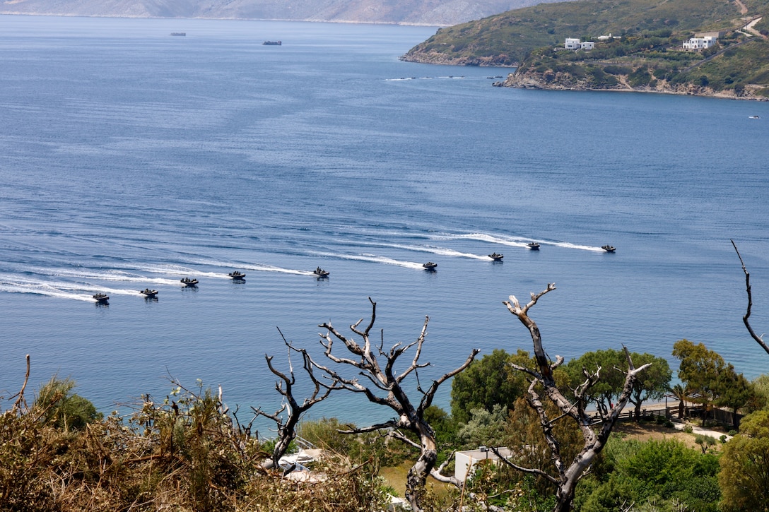 A group of boats head toward a shoreline.