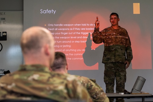 88th Security Forces combat arms instructor demonstrates how to safely hold the M18 9mm pistol as participants transition from the classroom to the firing range.