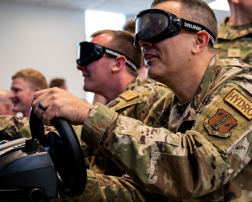 Pennsylvania Air National Guardsman, Master Sgt. James Helsel, assigned to the 171st Air Refueling Wing attempts to operate a vehicle in a distracted driver simulator while wearing goggles designed to replicate being visually impaired due to intoxication during the Health and Safety Awareness Day in Coraopolis, Pa. May 24, 2022.
