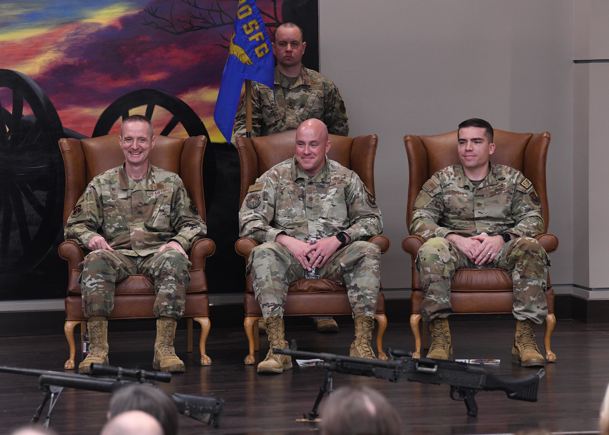 Col. Robert Ford Jr. (left), commander of the 90th Security Forces Group, Maj. Dexter Binion (middle), outgoing commander of the 90th Ground Combat Training Squadron, and Maj. Robert Hudspeth, incoming commander of 90 GCTS, listen to the opening remarks during a change of command ceremony May 26, 2021 in the Regional Training Institute building at Camp Guernsey, Wyoming. The change of command ceremony signifies the transition of command from Binion to Hudspeth. (U.S. Air Force photo by Airman 1st Class Darius Frazier.)