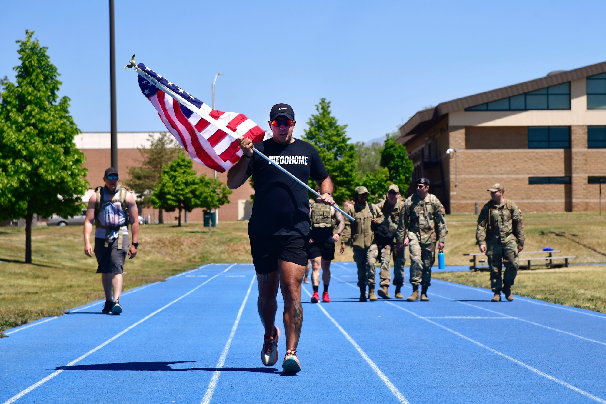 Technical Sgt. Christopher Baca running on the track holding the American flag.