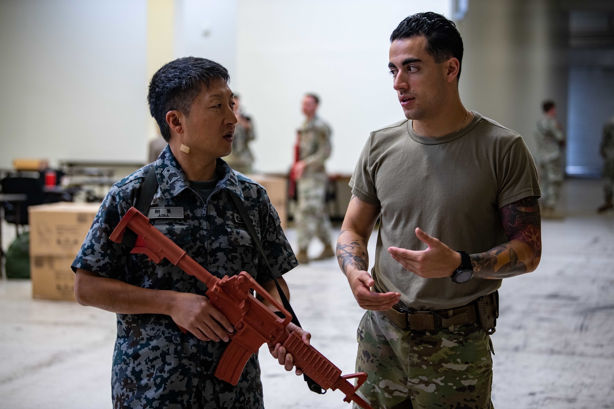 An Airman and a JASDF service member practice handling a weapon.