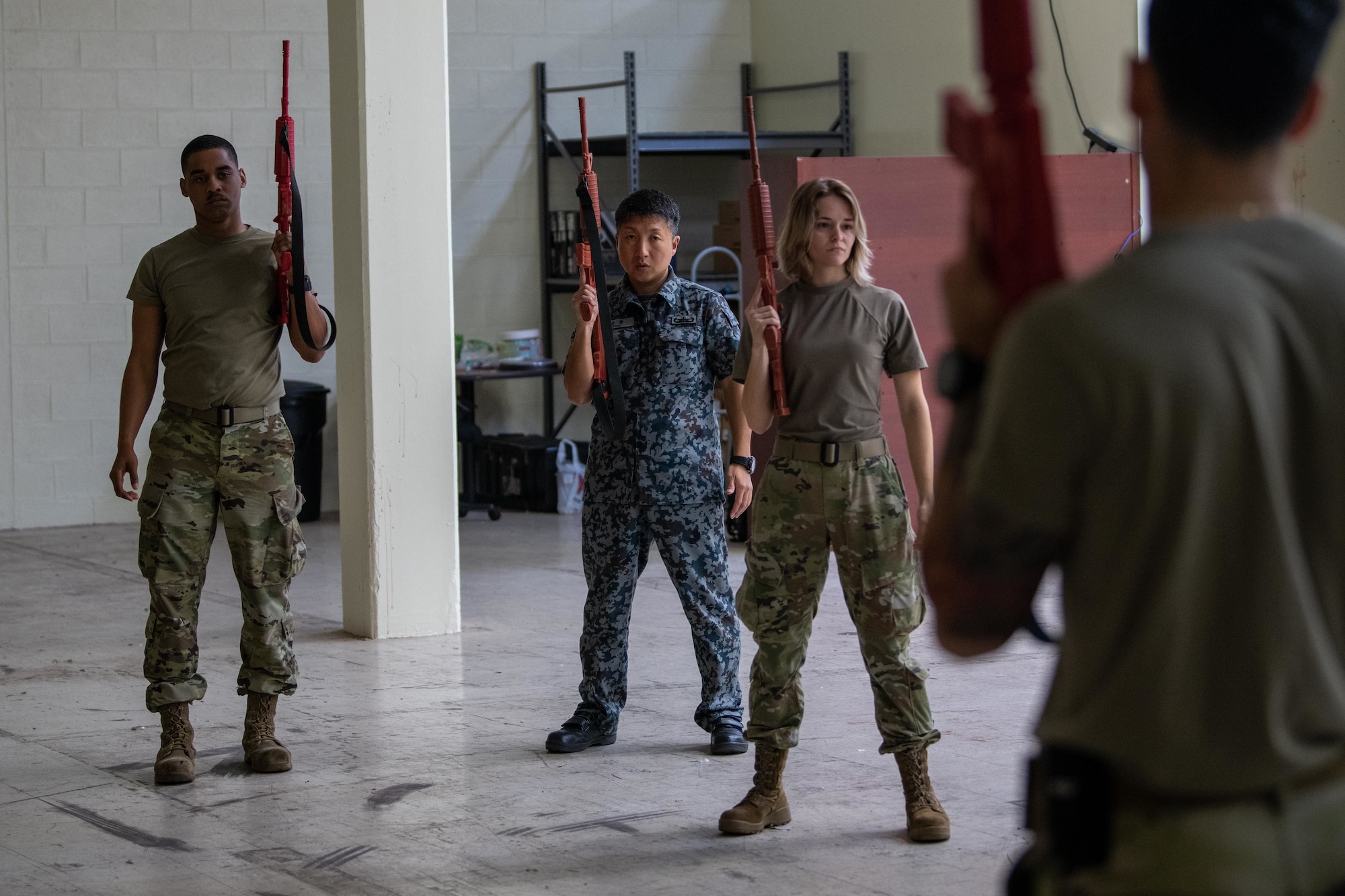 Airmen and a JASDF service member practice handling a weapon.