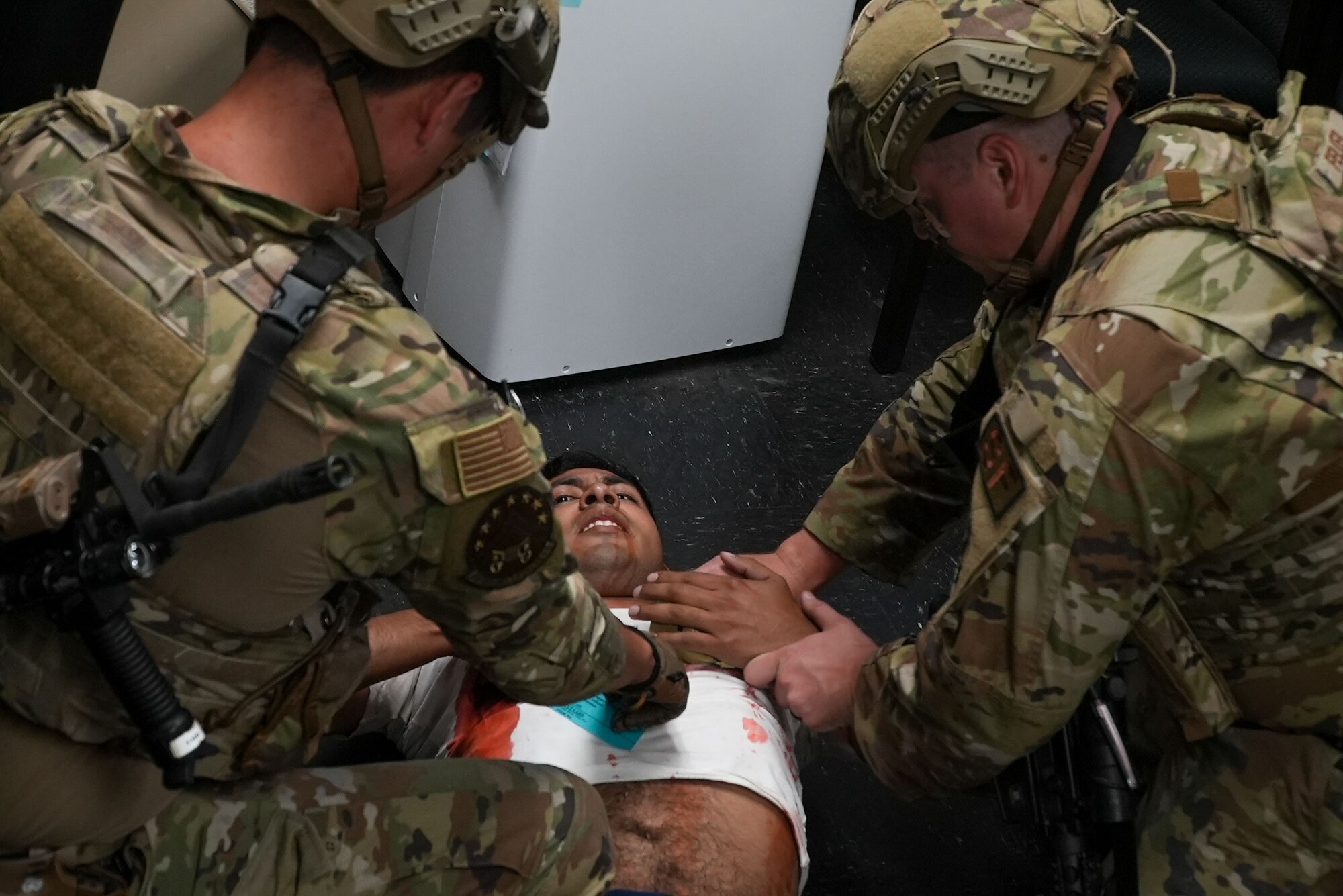Staff Sgt. Matthew Moses, 7th Security Forces Squadron Base Defense Operations Center controller, and Tech. Sgt. Shane Felker, 7th SFS Systems and Technology NCO in charge, practice giving first aid to Senior Airman Giovanny Rodriguez, 7th Munitions Squadron munitions stockpile manager and exercise role player, during an active shooter exercise at Dyess Air Force Base, Texas, May 24, 2022.