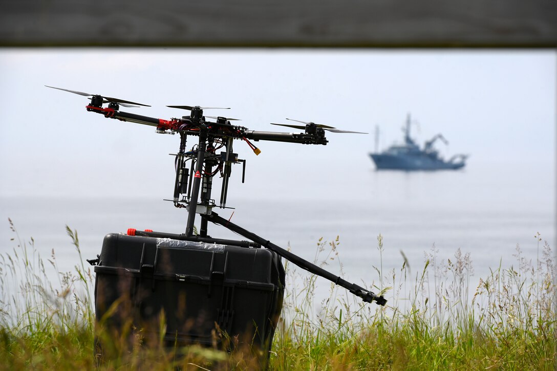 A small unmanned aerial system sits atop a box near the water.