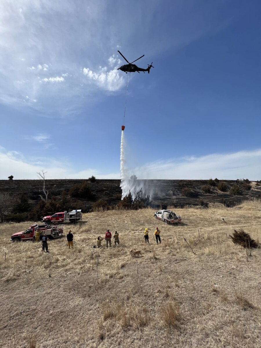 A Nebraska Army National Guard UH-60 Black Hawk helicopter drops water from a 780-gallon bucket onto a smoldering hot spot near Arapahoe, Nebraska, April 9, 2022. National Guard units throughout the nation have been fighting wildfires already, before the traditional start of the wildfire season in June.