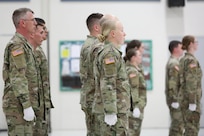 Group of uniformed soldiers in a formation at attention wearing white gloves