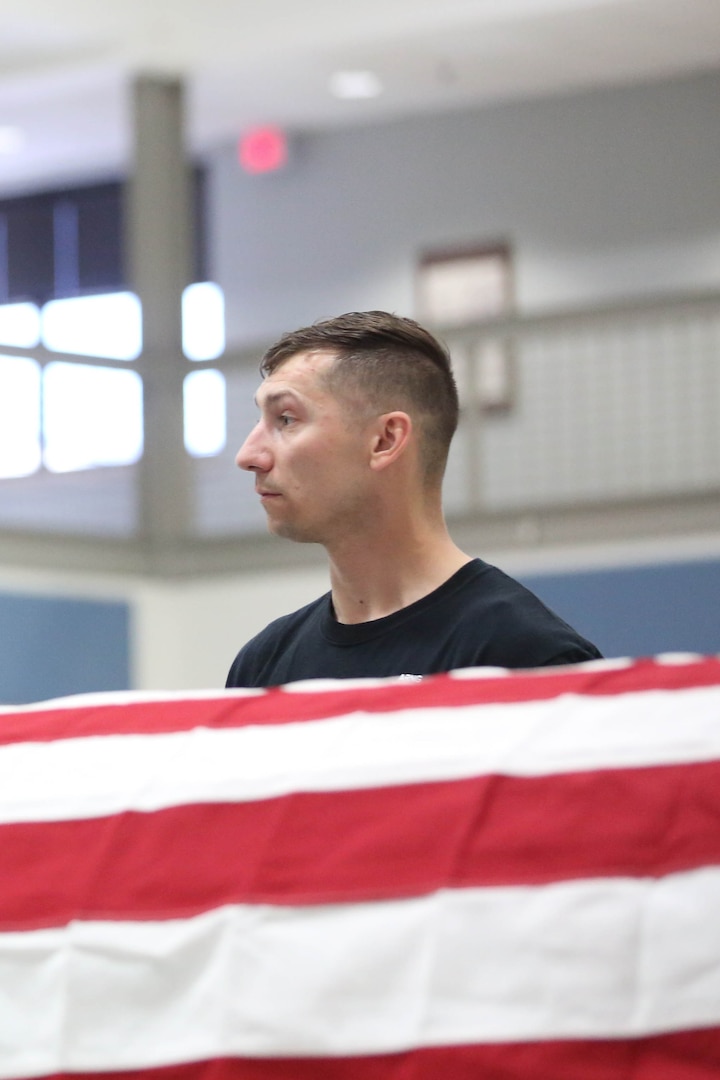 Man stands behind a flag covered coffin