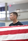 Man stands behind a flag covered coffin