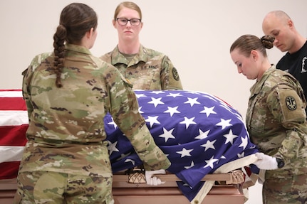 Soldiers prepare a flag covered coffin for movement