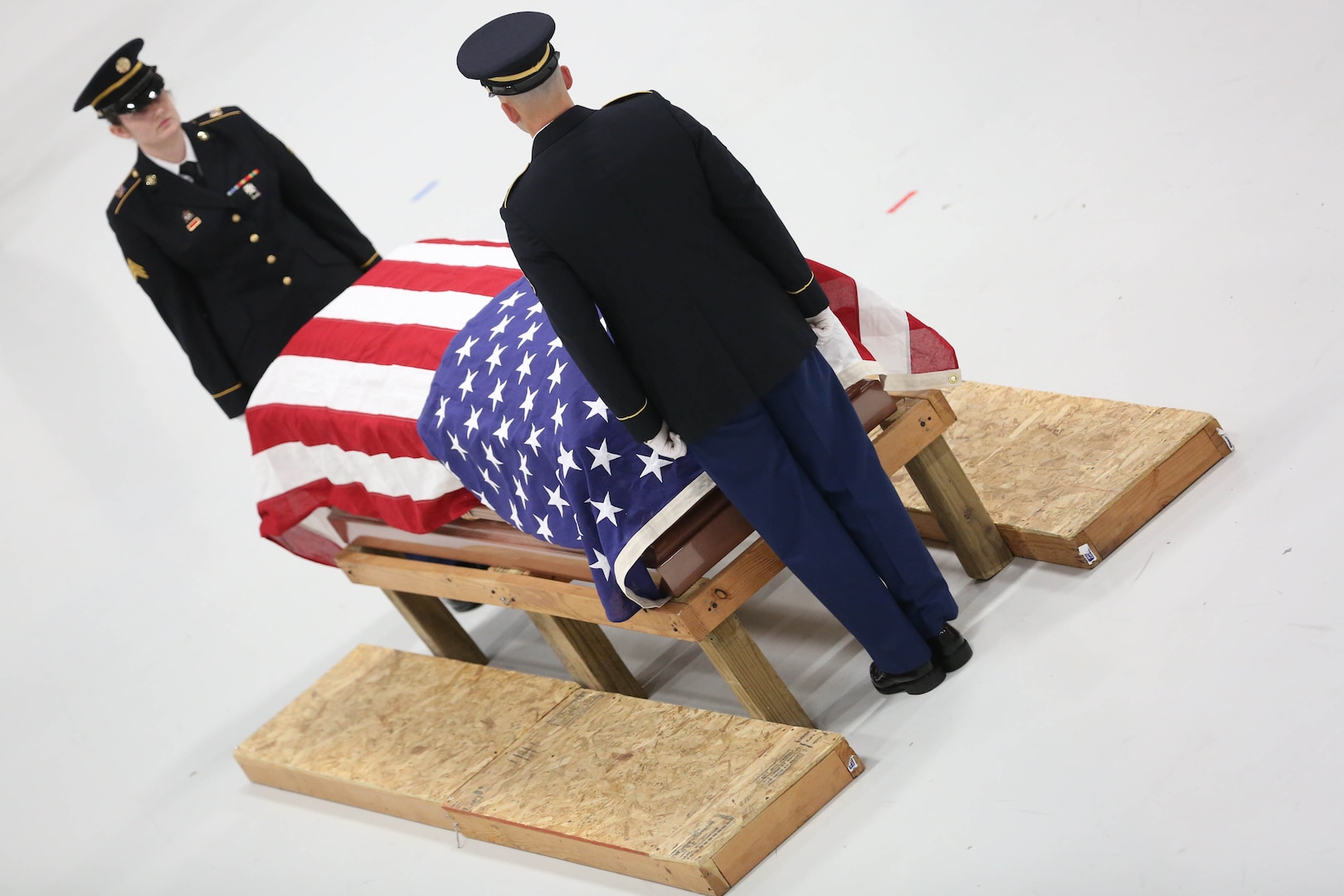 Two dress uniformed Soldiers at the ends of a flag draped coffin