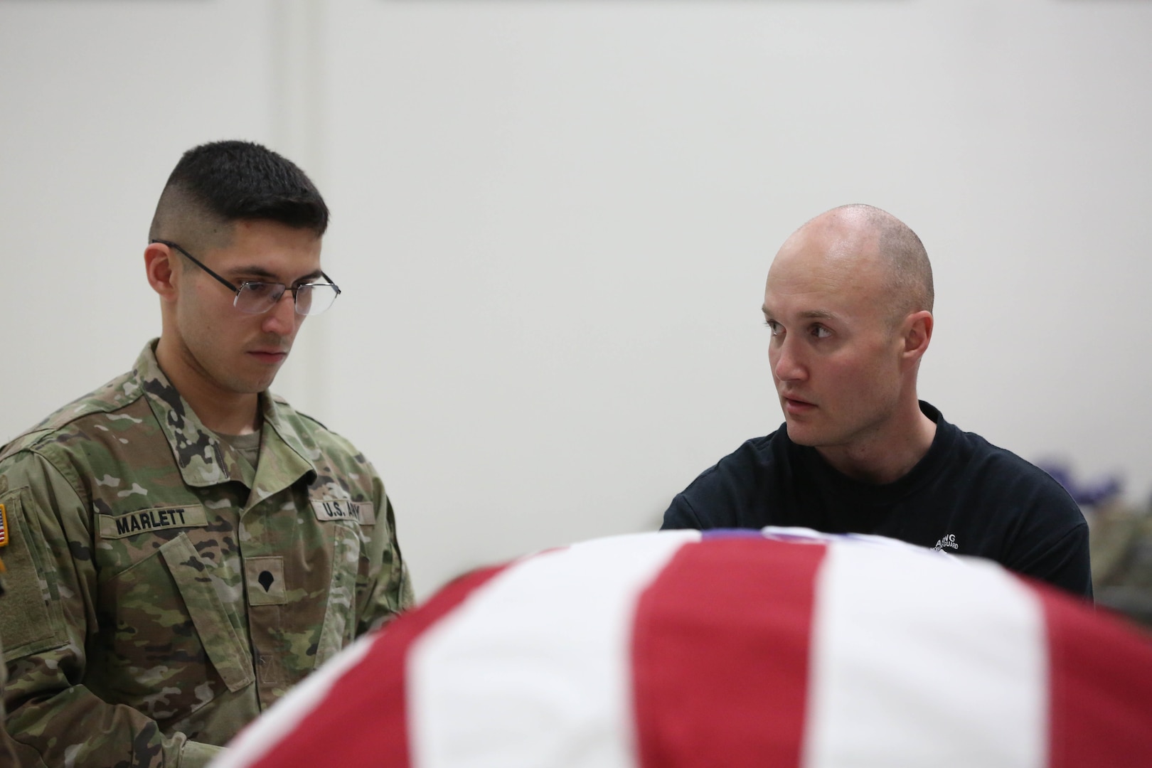Picture of two people standing behind a flag covered coffin