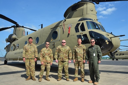 Left to right, Staff Sgt. Kyle Waller of the Illinois National Guard’s Company B, 238th General Support Aviation Battalion; Staff Sgt. Anthony Bearoff of the Pennsylvania National Guard’s Company B, 2-104th General Support Aviation Battalion; Staff Sgt. Robert Prigel, an instructor at the Eastern Army National Guard Aviation Site; Chief Warrant Officer 4 Kyle Kephart, an instructor pilots at EAATS; and Ron Henry, also an instructor pilot at EAATS, in front of a CH-47 Chinook helicopter on Muir Army Airfield at Fort Indiantown Gap, Pa., May 25, 2022. (This photo was altered to obscure an ID card)