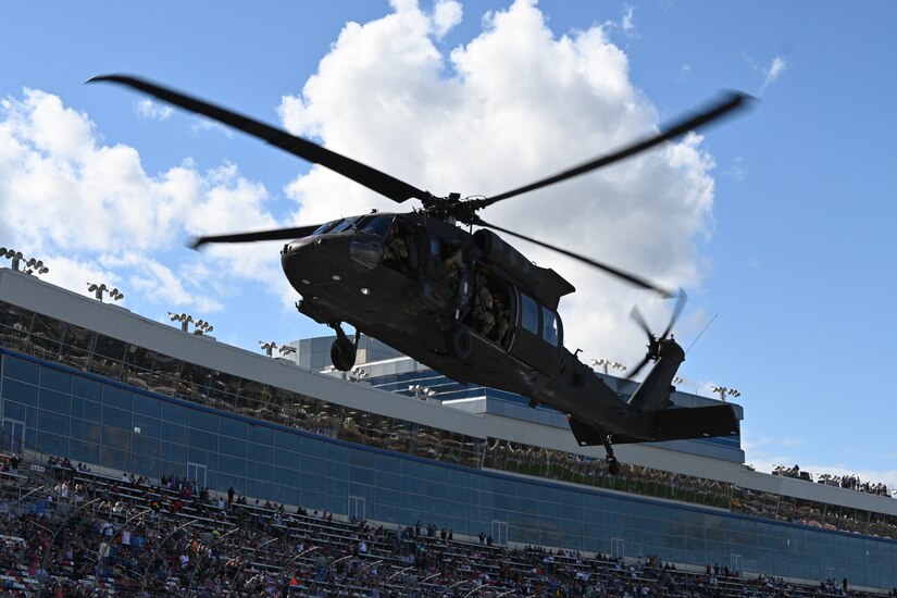 A helicopter hovers over the stands at a racetrack.