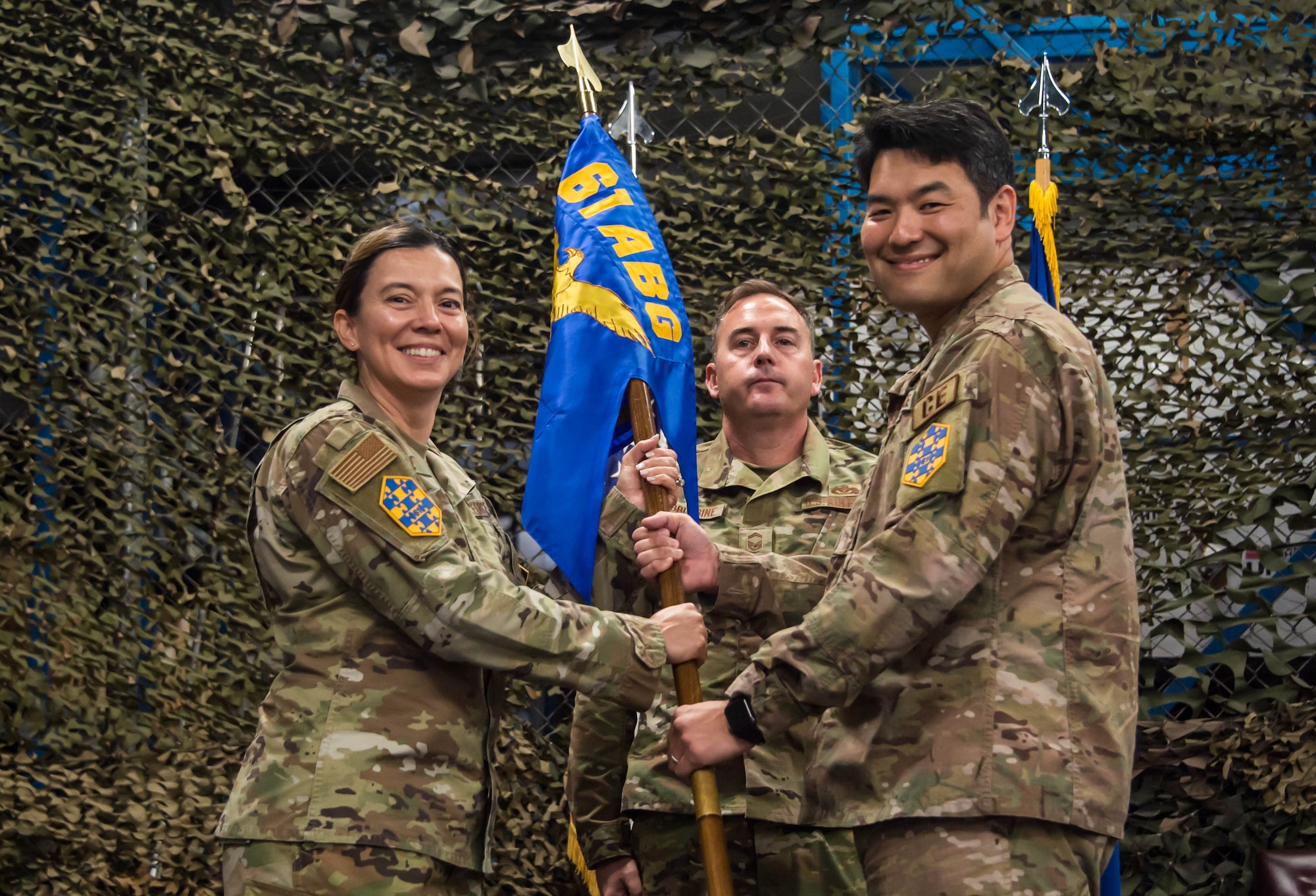 Col. Becky Beers, Los Angeles Garrison commander, left, accepts the 61st CELS, Civilian Engineer and Logistics Squadron, unit gideon from outgoing commander Lt. Col. Woo Chun, right at his change of command ceremony which was held in their warehouse on Monday.