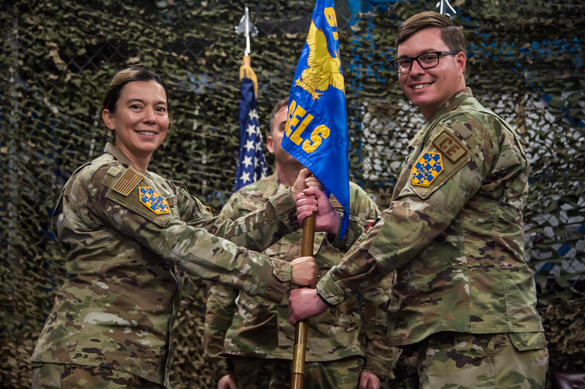 Col. Becky Beers, Los Angeles Garrison commander, left, turns over the 61st CELS command guidon to Lt. Col. Ryan Oot, new 61st CELS commander, right at his change of command ceremony which was held in their warehouse on Monday.