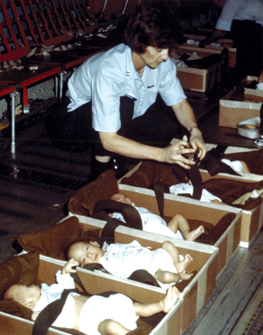 Image of a woman securing babies on a plane.