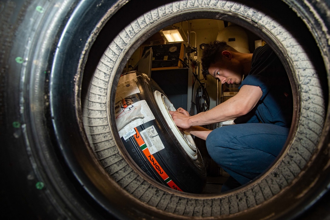An  airman screws bearings into a tire.