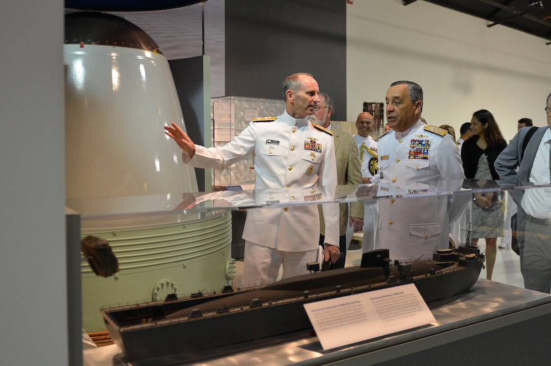 Image of military men, one giving the other a tour with a group of people in tow.