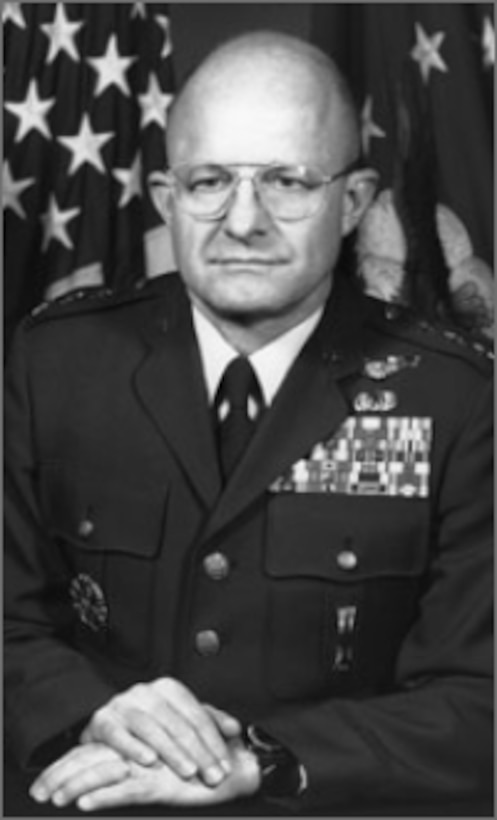 Image of a decorated military man, sitting in front of an American flag.
