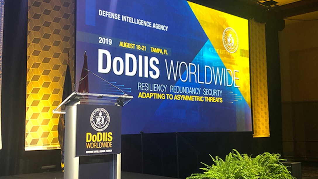 Image of a stage for DoDIIS Worldwide in 2019 with plant in front.