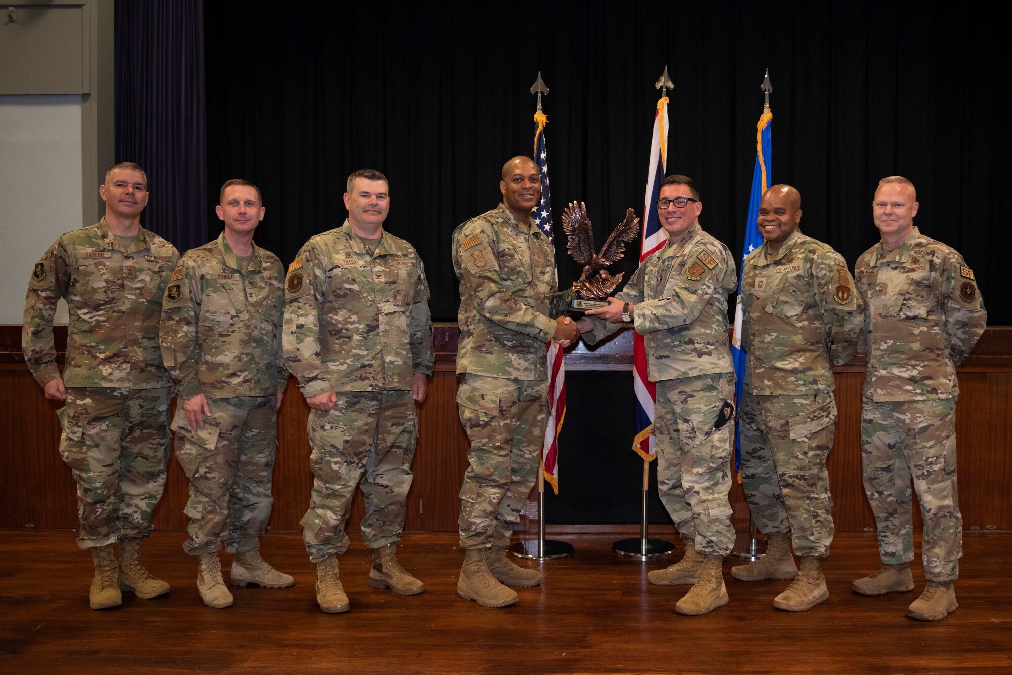U.S. Air Force Chief Master Sgt. Donald S. Gallagher, center left, 20th Security Forces career field manager, and Chief Master Sgt. Donald S. Gallagher, right, 20th Security Forces career field manager, present the 2021 Air Force Best Small Security Forces Squadron to the 422nd Security Forces Squadron Airmen during a visit to Royal Air Force Croughton, England, May 23, 2022. Gallagher and Collins visited RAF Croughton to meet and recognize the 422nd SFS Airmen. (U.S. Air Force photo by Senior Airman Jennifer Zima)