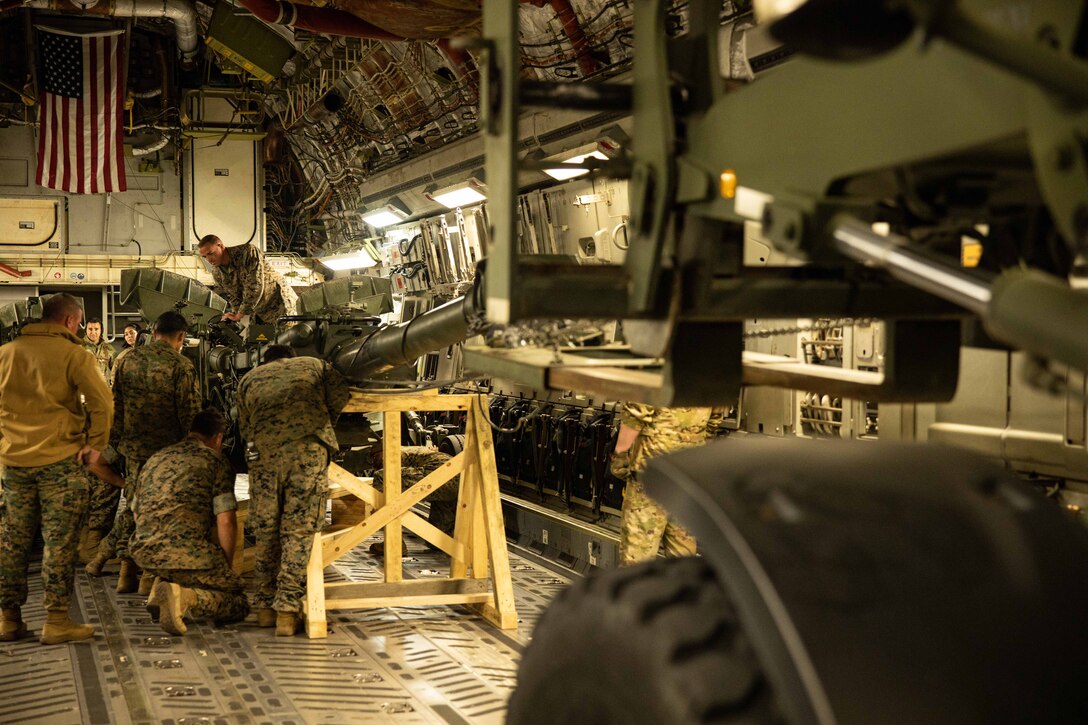 Service members load a weapon on to an aircraft.