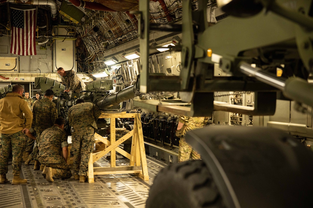 Service members load a weapon on to an aircraft.