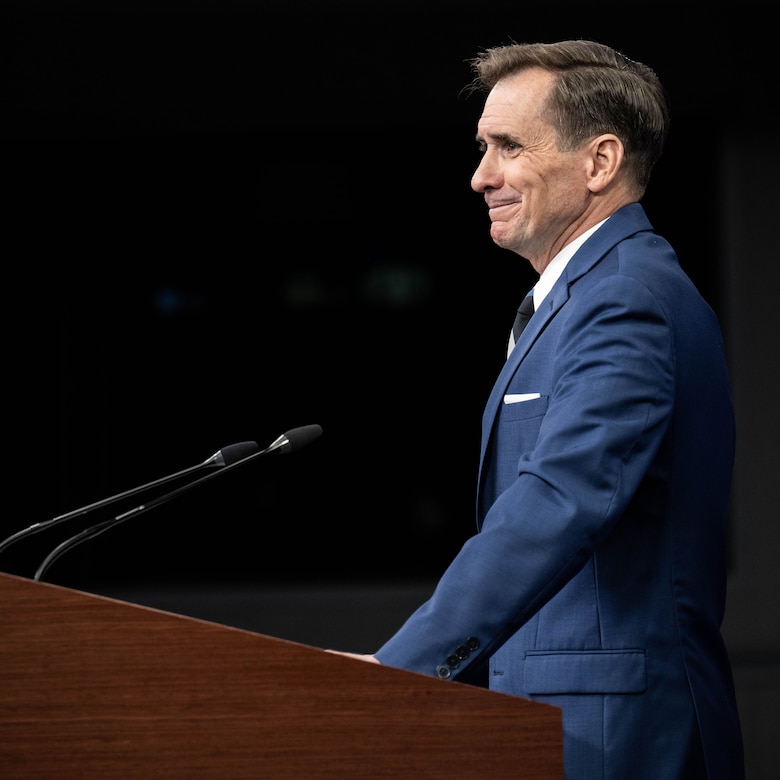 Pentagon Press Secretary John F. Kirby shown in profile standing at lectern.