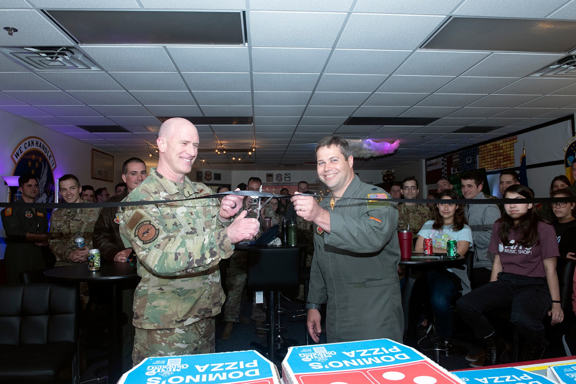 Two Air Force officers cutting a ribbon with audience in the background.