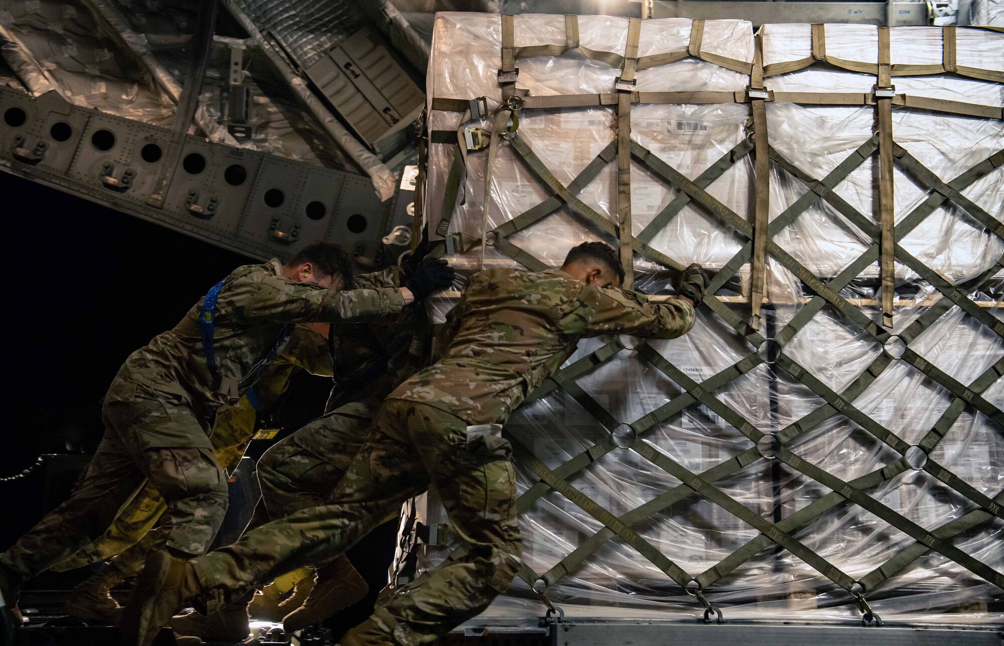 Airmen assigned to the 721st Aerial Port Squadron load a pallet of infant formula onto a C-17 Globemaster lll