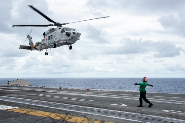 220526-N-BR419-1050 PHILIPPINE SEA (May 26, 2022) Aviation Machinist’s Mate Airman Dominique Mendez-Lopez, from Brandywine, Maryland, directs a Japan Maritime Self-Defense Force (JMSDF) SH-60K Seahawk, attached to the JMSDF destroyer JS Teruzuki (DD 116), on the flight deck of the U.S. Navy’s only forward-deployed aircraft carrier USS Ronald Reagan (CVN 76). The U.S. Navy and JMSDF routinely conduct naval exercises together, strengthening the U.S.-Japan alliance and maintaining a free and open Indo-Pacific region. Ronald Reagan, the flagship of Carrier Strike Group 5, provides a combat-ready force that protects and defends the United States, and supports alliances, partnerships and collective maritime interests in the Indo-Pacific region. (U.S. Navy photo by Mass Communication Specialist 3rd Class Oswald Felix Jr.)