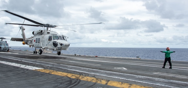 220526-N-BR419-1065 PHILIPPINE SEA (May 26, 2022) Aviation Machinist’s Mate Airman Dominique Mendez-Lopez, from Brandywine, Maryland, directs a Japan Maritime Self-Defense Force (JMSDF) SH-60K Seahawk, attached to the JMSDF destroyer JS Teruzuki (DD 116), on the flight deck of the U.S. Navy’s only forward-deployed aircraft carrier USS Ronald Reagan (CVN 76). The U.S. Navy and JMSDF routinely conduct naval exercises together, strengthening the U.S.-Japan alliance and maintaining a free and open Indo-Pacific region. Ronald Reagan, the flagship of Carrier Strike Group 5, provides a combat-ready force that protects and defends the United States, and supports alliances, partnerships and collective maritime interests in the Indo-Pacific region. (U.S. Navy photo by Mass Communication Specialist 3rd Class Oswald Felix Jr.)