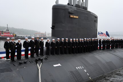 Crewmembers attached to the Virginia-class fast attack submarine USS Oregon (SSN 793) man the ship during a commissioning ceremony in Groton, Conn., May 28, 2022.