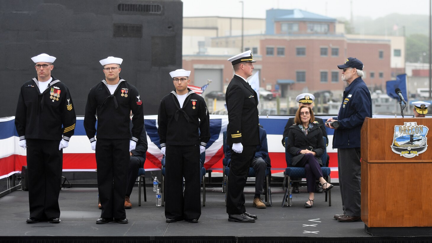 Retired Senior Chief Petty Officer Arlo Gatchel, right, passes a long glass to Lt. Thomas Mc Sweeny, who ceremonially set the “first watch” during a commissioning ceremony for the Virginia-class fast attack submarine USS Oregon (SSN 793) in Groton, Conn., May 28, 2022.
