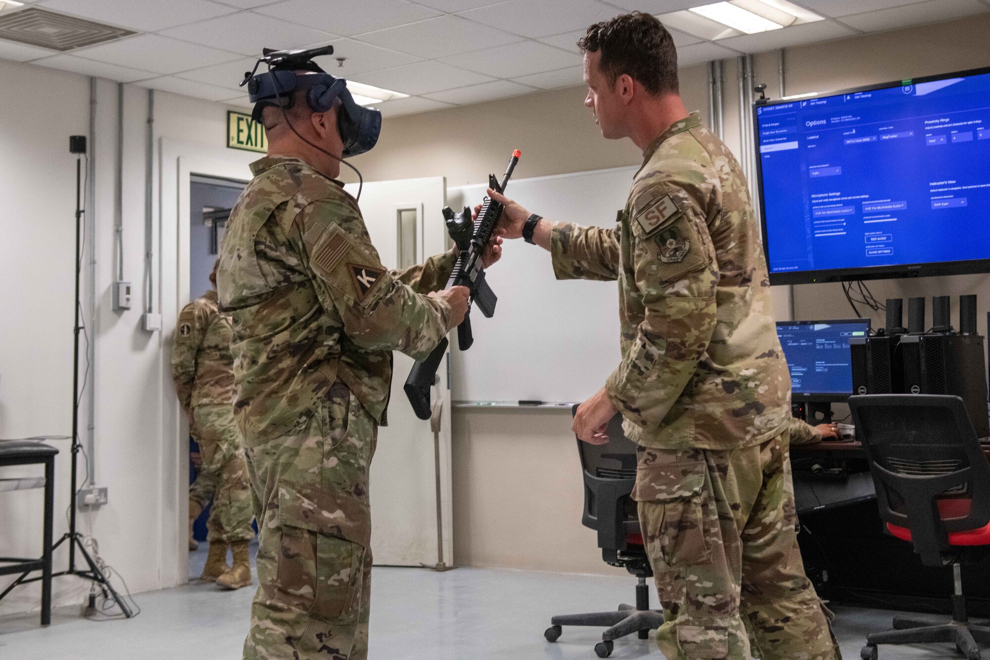 U.S. Air Force Tech Sgt. Jesse Ermer, a 379th Air Expeditionary Security Forces Squadron member, hands a training rifle to U.S. Air Force Brig. Gen. Gerald Donohue, 379th Air Expeditionary Wing Commander, for use in a virtually-simulated training exercise on Al Udeid Air Base, Qatar, May 24, 2022. The Street Smart VR Simulator allows airmen to practice different situations with different tools or weapons. (U.S. Air National Guard photo by Airman 1st Class Constantine Bambakidis)