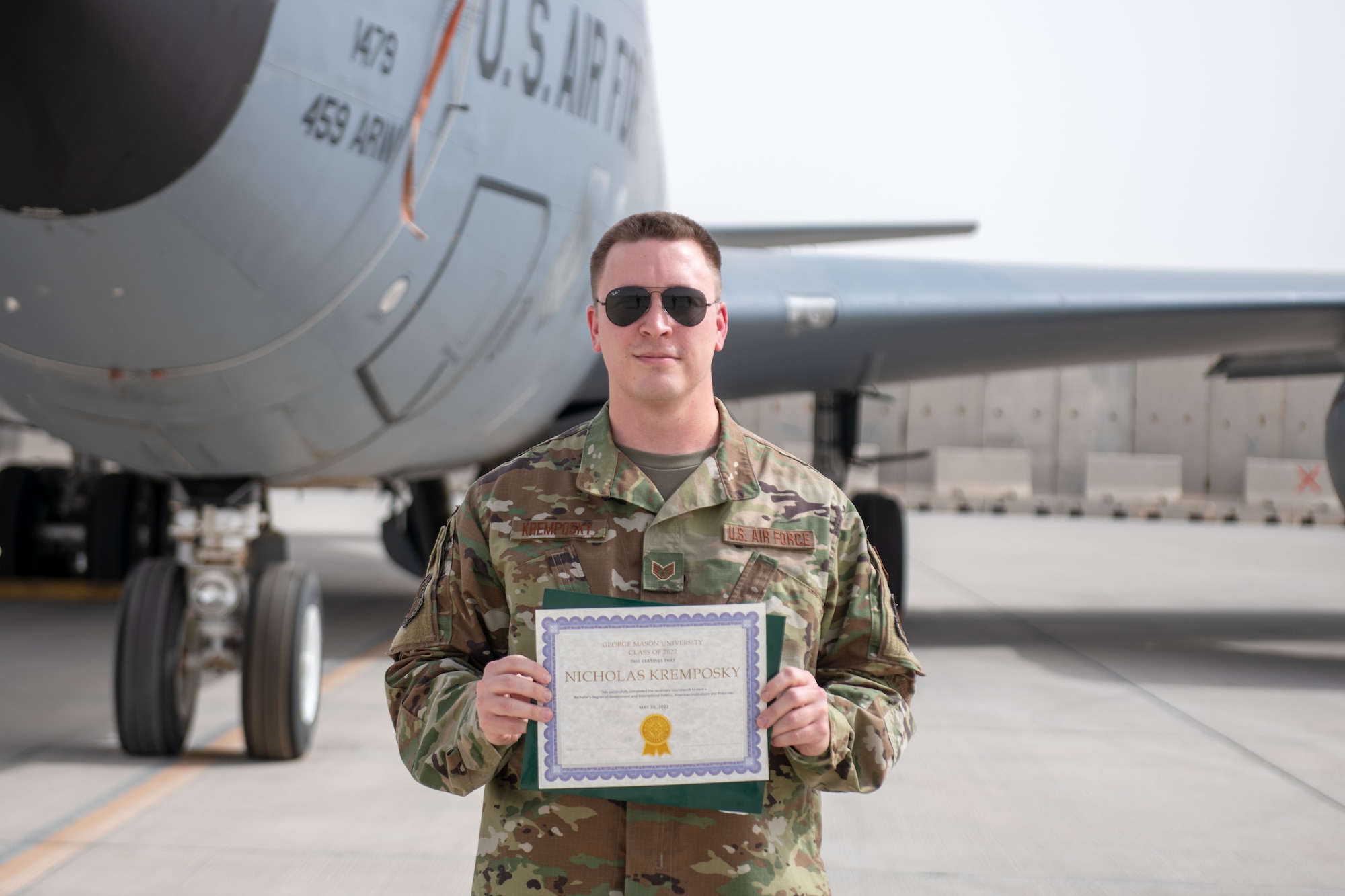 U.S. Air Force Staff Sgt. Nicholas Kremposky poses in front of a KC-135 with his college diploma on Al Udeid Air Base, Qatar, May 26, 2022. Kremposky graduated with his bachelor's degree during his deployment on AUAB, and is currently pursuing a master's degree. (U.S. Air National Guard photo by Airman 1st Class Constantine Bambakidis)