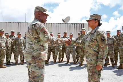 Senior Enlisted Advisor Tony Whitehead, senior enlisted advisor to the chief, National Guard Bureau, presents a coin of excellence to Army Spc. Monica Iriarte of the Guam National Guard’s 1224th Engineer Support Company on Guam, May 23, 2022. Iriarte is part of a security forces mission staffed and equipped by the Guam Guard to protect air defense assets critical to Guam’s defense.