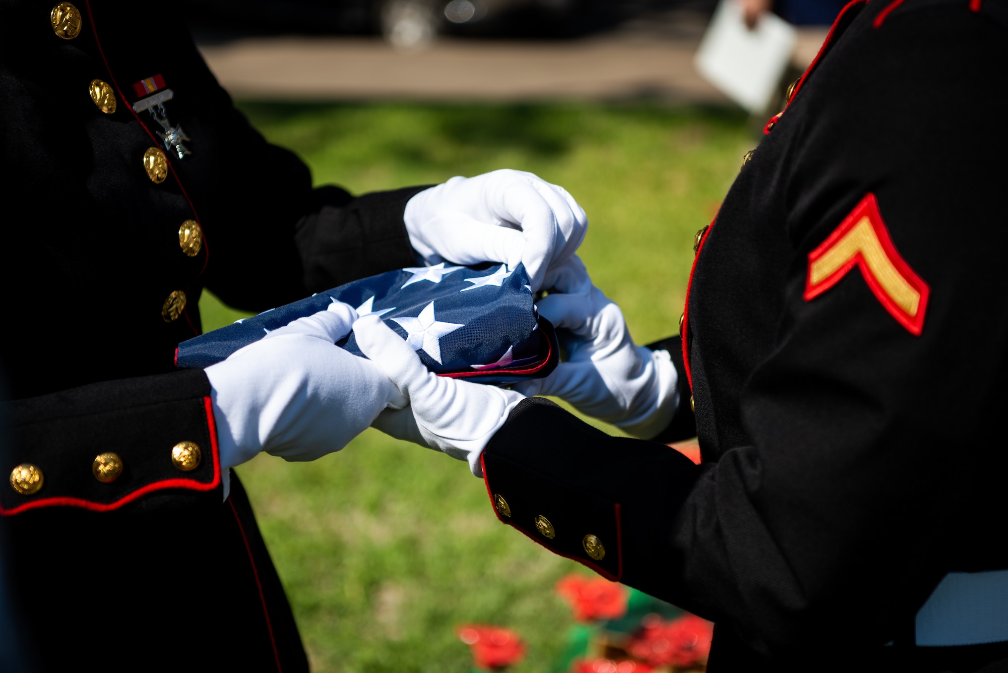 Two Marines from Marine Corps Detachment Goodfellow fold the American flag during a Memorial Day service at the Tom Green County Courthouse Lawn, San Angelo, Texas, May 30, 2022. The folded flag was presented to Mrs. Janet Worden, a gold star spouse in attendance of the ceremony. (U.S. Air Force photo by Senior Airman Michael Bowman)
