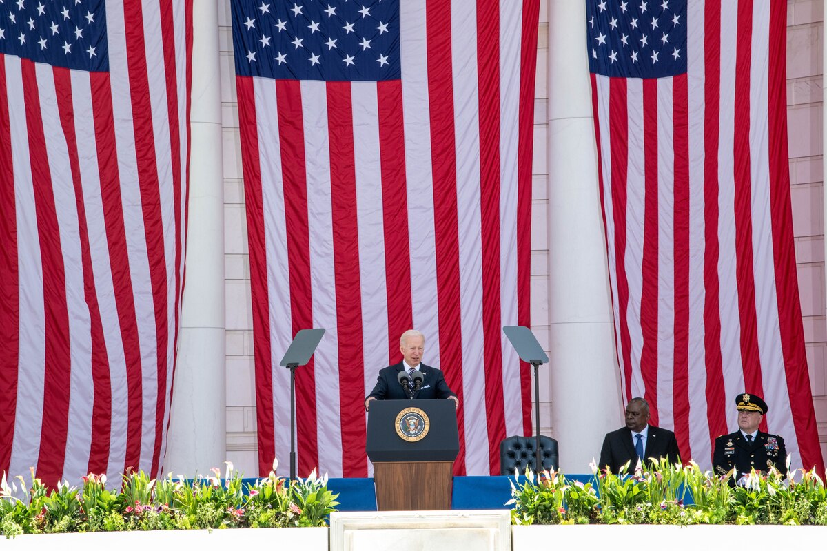 President Joe Biden speaks from a stage with large American flags behind him.